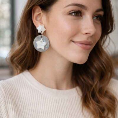 Pendientes artesanales de estrellas blancas puestos en modelo con jersey claro