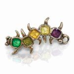 Broche artesanal único Amaro con esmaltes en tonos verde, amarillo, ámbar y morado sobre base metálica