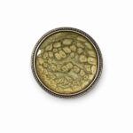 Broche redondo artesanal en tonos oliva y dorado con textura orgánica y marco metálico plateado