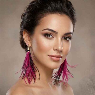 Pendientes de plumas Mahi artesanales en fucsia y negro con detalle dorado sobre modelo