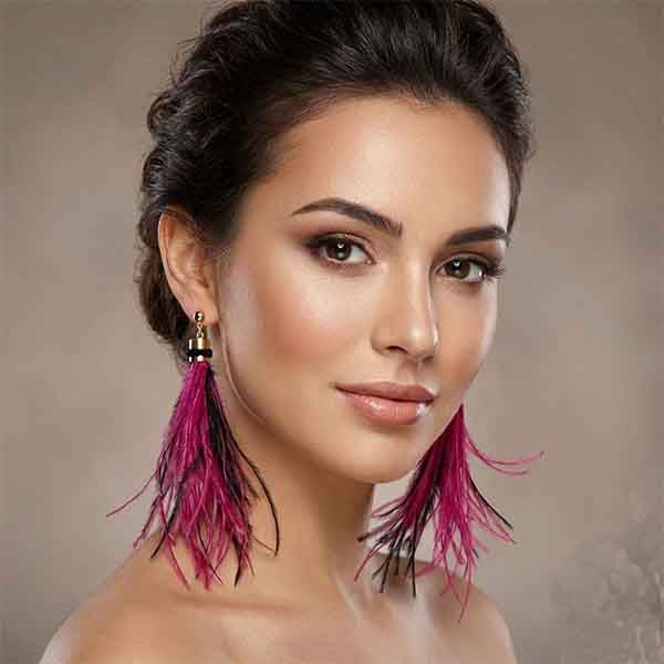Pendientes de plumas Mahi artesanales en fucsia y negro con detalle dorado sobre modelo