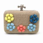Clutch Marga Flores rígido con flores de colores sobre fondo blanco