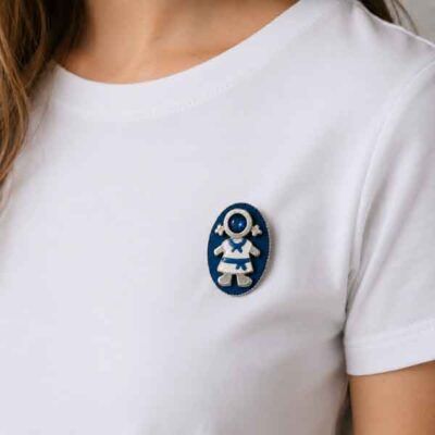 Broche Ejeánica con cristal azul pintado a mano sobre camiseta blanca. Diseño artesanal de Turquesa y Más inspirado en Ejea de los Caballeros.