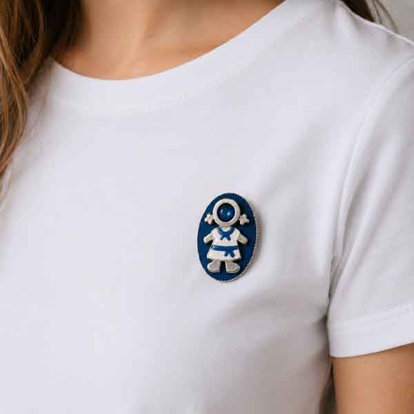 Broche Ejeánica con cristal azul pintado a mano sobre camiseta blanca. Diseño artesanal de Turquesa y Más inspirado en Ejea de los Caballeros.