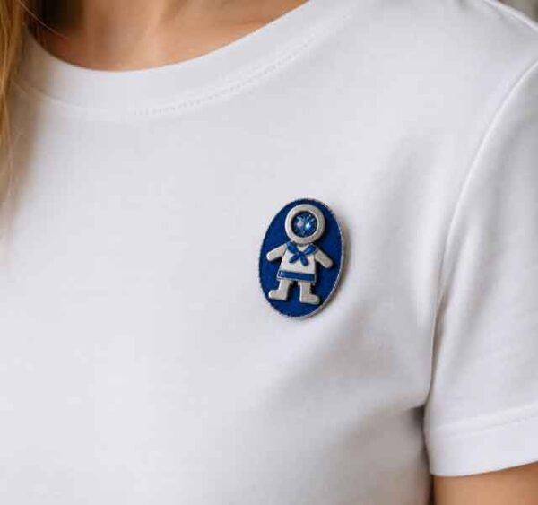 Broche Ejeánico con cristal pintado a mano sobre camiseta blanca. Diseño artesanal de Turquesa y Más inspirado en Ejea de los Caballeros.