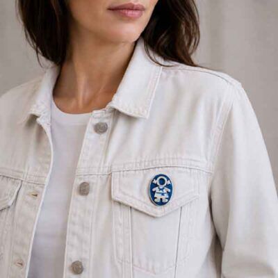 Broche Ejeánica pintado a mano colocado en el bolsillo de una cazadora vaquera blanca.