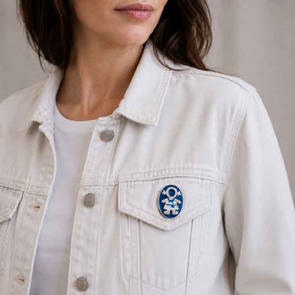 Broche Ejeánica pintado a mano colocado en el bolsillo de una cazadora vaquera blanca.