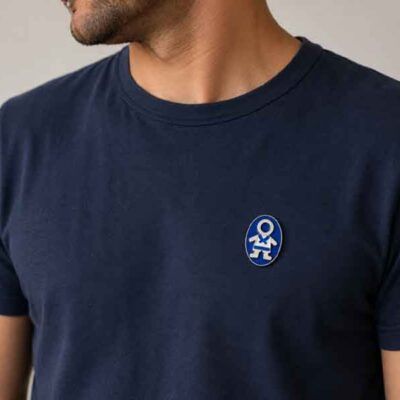 Broche Ejeánico pintado a mano colocado en una camiseta de hombre azul marino.