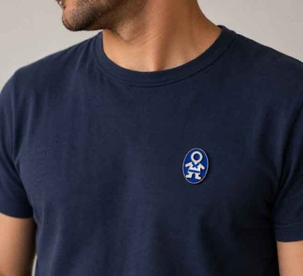 Broche Ejeánico pintado a mano colocado en una camiseta de hombre azul marino.
