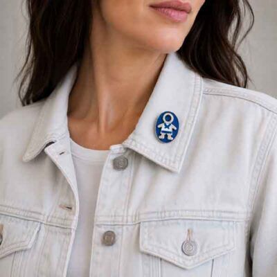 Broche Ejeánico pintado a mano colocado en la solapa de una cazadora vaquera blanca.