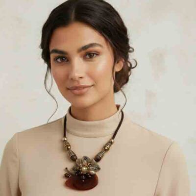 Mujer con collar Alicia marrón y dorado con piedra en forma de media luna y flor de bolas facetadas, sobre jersey beige.