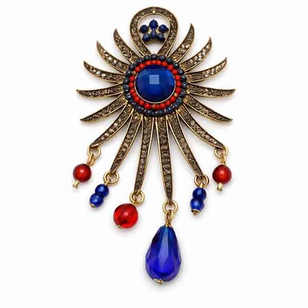 Broche Sol Kanpur de inspiración vintage en oro viejo Broche Sol Kanpur en oro viejo con piedra azul central y abalorios rojos y azules