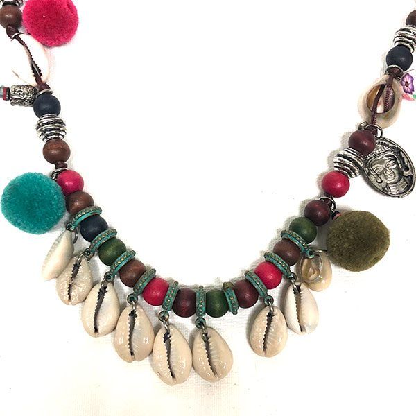 Detalle del Collar Alexis Pompones con cuentas de madera, pompones de lana y conchas naturales en tonos verdes, rojos y beige.
