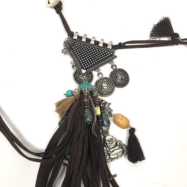 Detalle del Collar boho Amadeo con borla de ante marrón, colgantes metálicos, cuentas turquesa y figura decorativa plateada.