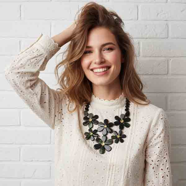 Modelo sonriendo con blusa beige calada luciendo el collar Lea, con flores de resina en tonos verdes y cristal brillante en el centro de cada flor.