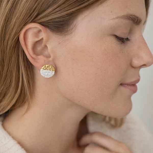 Pendientes de porcelana artesanales blanco y oro colocados en la oreja