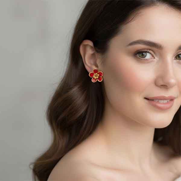 Pendientes de porcelana pintados a mano en forma de flor roja colocados en oreja de mujer, diseño artesanal Turquesa y Más.