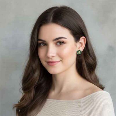 Pendientes de porcelana pintados a mano en forma de flor verde colocados en oreja de mujer, diseño artesanal Turquesa y Más.