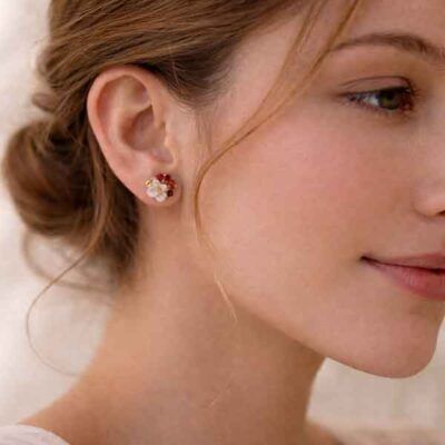 Pendientes Jolie de botón en porcelana artesanal con forma de flor en blanco nacarado, esmalte granate y detalles en oro, puestos en oreja