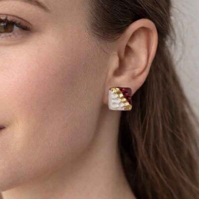 Pendientes Jolie de porcelana artesanales en forma cuadrada blanco nacarado, granate y oro puestos en la oreja