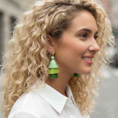 Pendientes Carla artesanales de borlas en tonos verdes sobre modelo con camisa blanca