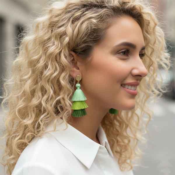 Pendientes Carla artesanales de borlas en tonos verdes sobre modelo con camisa blanca