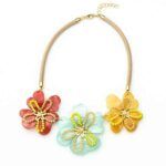 Collar Montsi floral con tres flores grandes de resina en tonos rojo, azul celeste y dorado, decoradas con cuentas de vidrio y cordón beige ajustable.