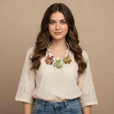 Modelo luciendo el collar Montsi con tres flores de resina nacarada en tonos rojo, azul celeste y dorado, decoradas con cuentas de vidrio.