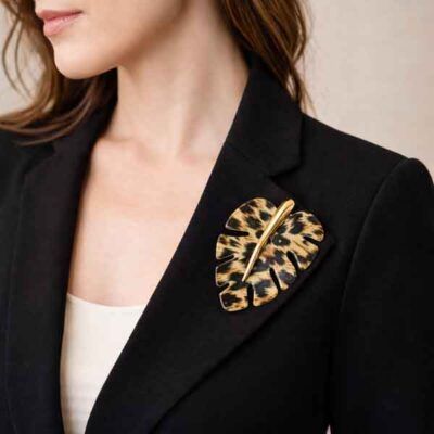 Broche leo efecto animal print colocado en la solapa de una chaqueta negra