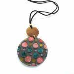 Collar Piruleta de resina con cordón negro y medallón gris con topos de colores en tonos rosa, turquesa y dorado.