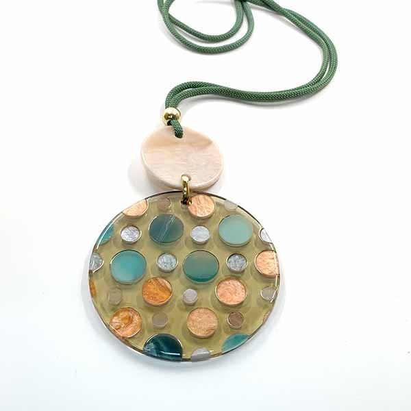 Collar Piruleta de resina con cordón verde y medallón circular en tonos turquesa, dorado y beige con topos de colores.
