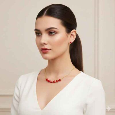 Modelo luciendo el collar Trin rojo artesanal con triángulos de coral y cadena dorada.