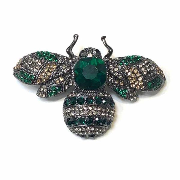 BROCHE HAYAR CRISTAL Broche Hayar con cristales verde botella y gris ahumado en forma de abeja sobre fondo blanco, fotografía de producto profesional.