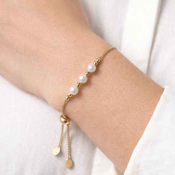 Pulsera de acero dorado con perlas Ragna puesta en la muñeca de una modelo