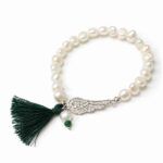 Pulsera de perlas con ala y borla verde sobre fondo blanco