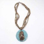 Collar con colgante turquesa y cuentas marrones sobre fondo blanco