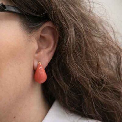 Pendientes Goittia esmaltados en color coral puestos en la oreja