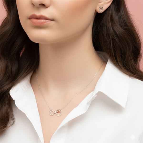 Collar de plata con siluetas Mickey y Minnie y lazo rosa llevado por mujer con camisa blanca