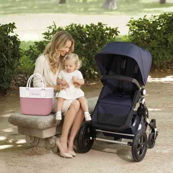 Madre con su hija y bolso O bag Mini rosa con borde personalizado Turquesa y Más junto a un cochecito