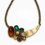 Collar Atenea de piedras de colores sobre fondo blanco, diseño elegante en tonos dorado, ámbar y verde.