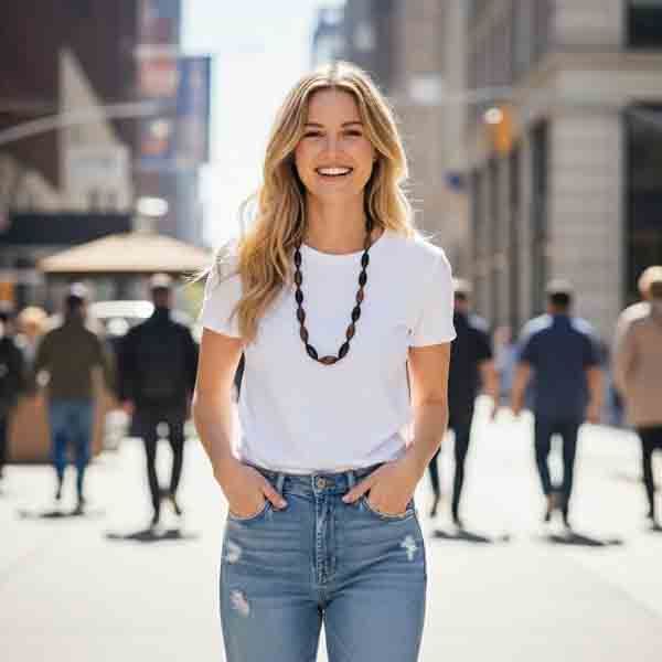 Modelo con camiseta blanca y vaqueros luciendo el collar Calista de resina facetada en tonos azul, beige y caramelo, bisutería moderna para mujer.