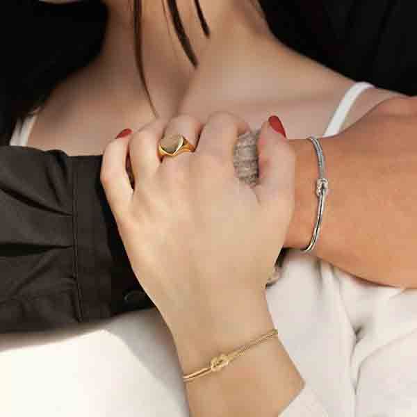 Pareja abrazada luciendo pulseras Nudo de Amor en plata y oro