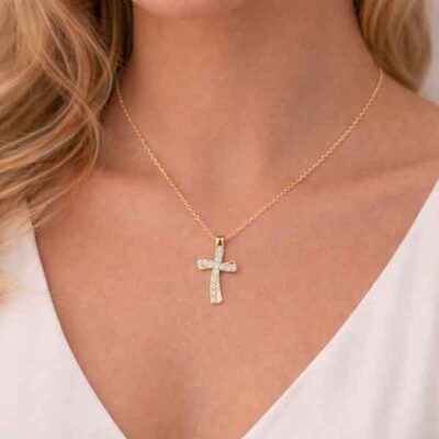 Collar de cruz ondulada bañado en oro con circonitas blancas sobre el cuello de una modelo