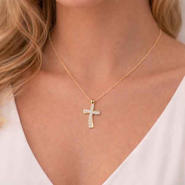 Collar de cruz ondulada bañado en oro con circonitas blancas sobre el cuello de una modelo