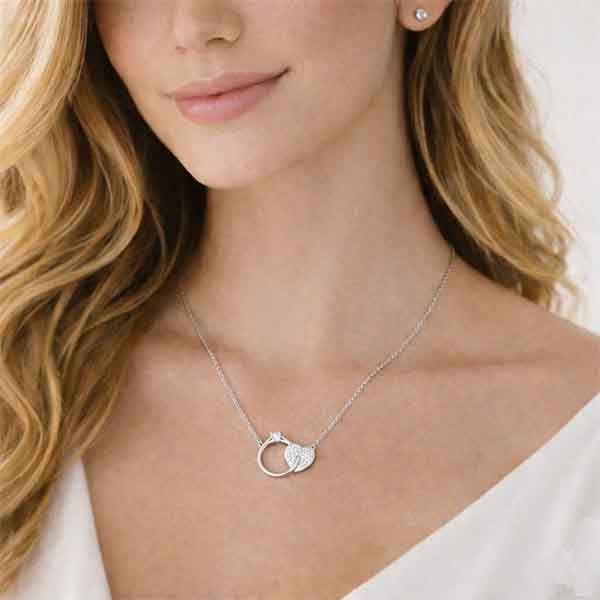 Modelo luciendo collar de plata con anillo y corazón entrelazados con circonitas blancas