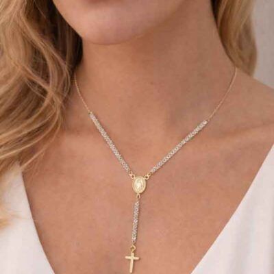 Collar rosario dorado con circonitas blancas y cruz sobre modelo, diseño elegante y luminoso