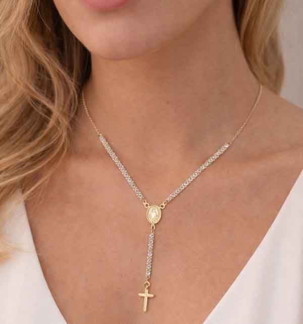 Collar rosario dorado con circonitas blancas y cruz sobre modelo, diseño elegante y luminoso