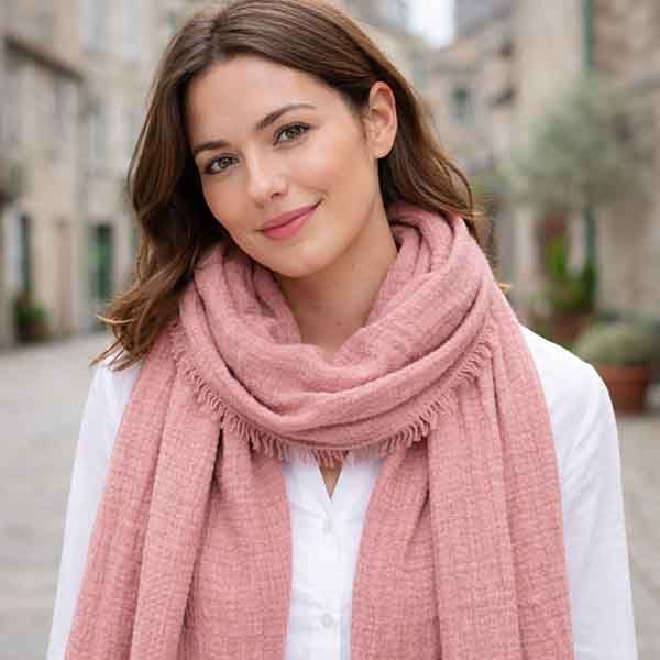 Foulard rosa de viscosa con textura ligeramente rizada y flecos finos llevado por modelo