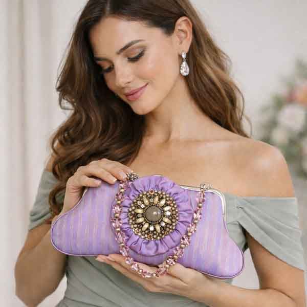 Invitada con vestido verde salvia sosteniendo clutch lavanda con broche joya y cadena rosa