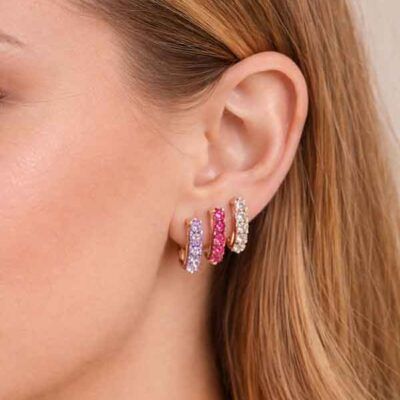 Pendientes tennis en oro rosa con circonitas lila, fucsia y blancas colocados en la oreja en combinación triple
